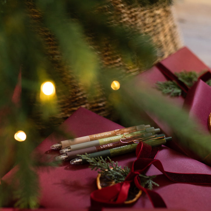 All four of the Identity Pen Set in the package on a red Christmas Present wrapped with a red ribbon and next to a green tree