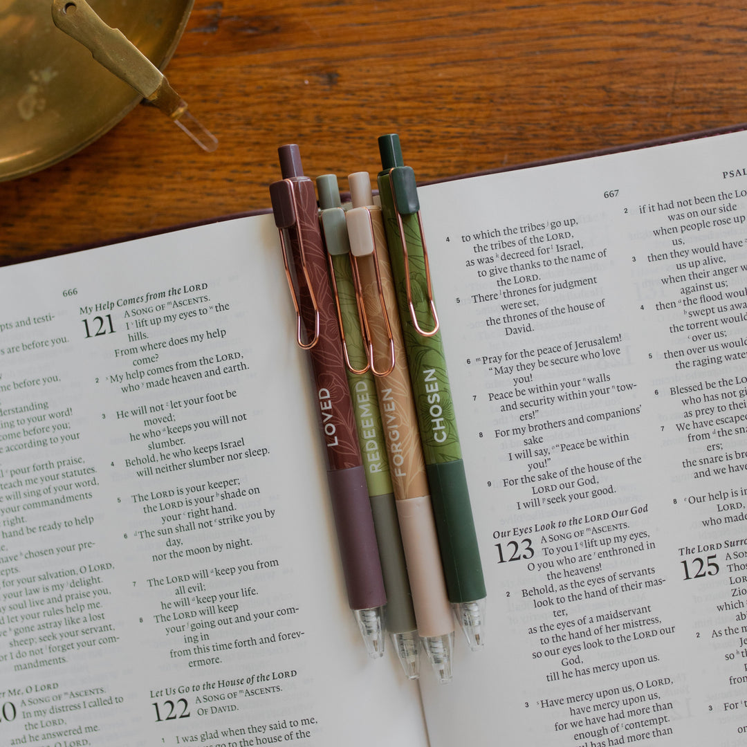 All four of the Identity Pen Set on an open bible and on a wooden table