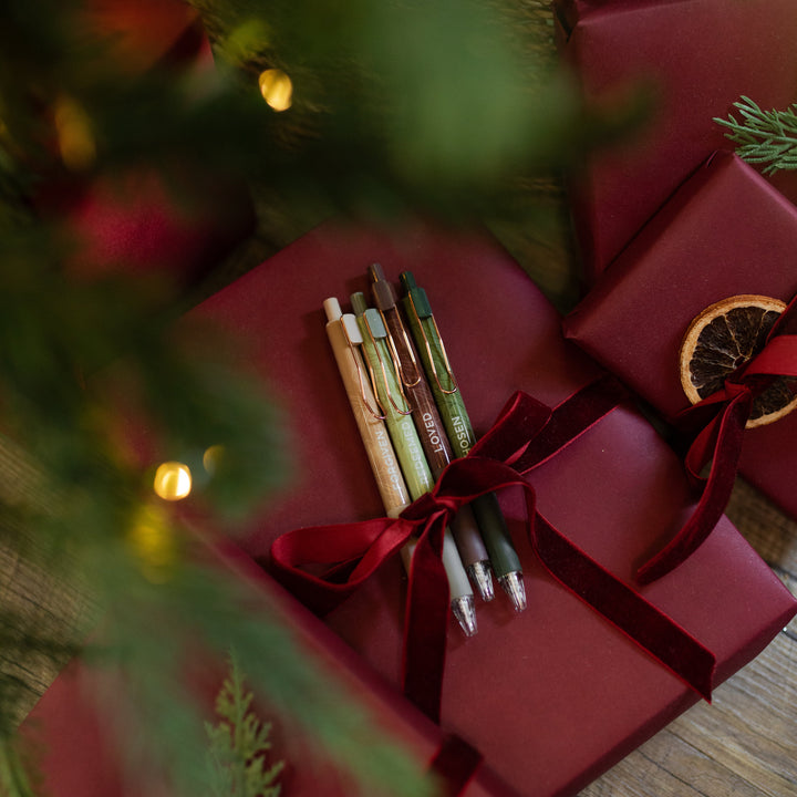 All four of the Identity Pen Set on an red package wrapped under with a red ribbon