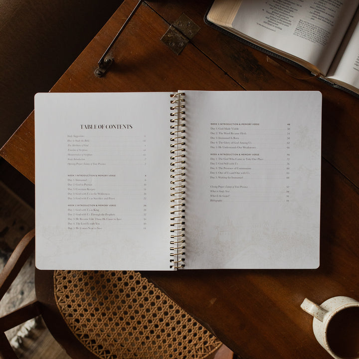 The Immanuel Spiral cover opened to the table of contents page on a wooden table near a coffee cup