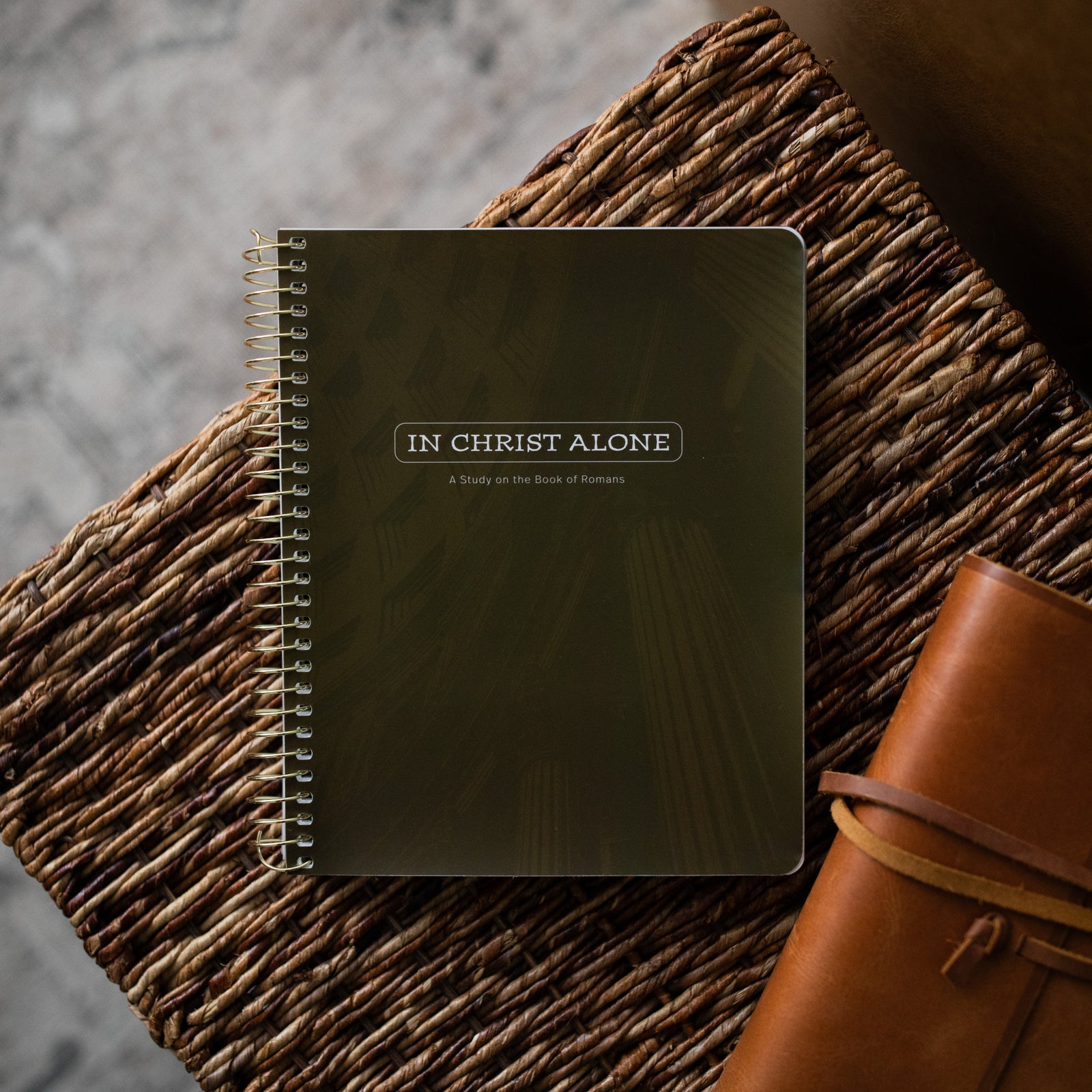 In Christ Alone Mens Study cover on an woven box next to a leather wrapped bible