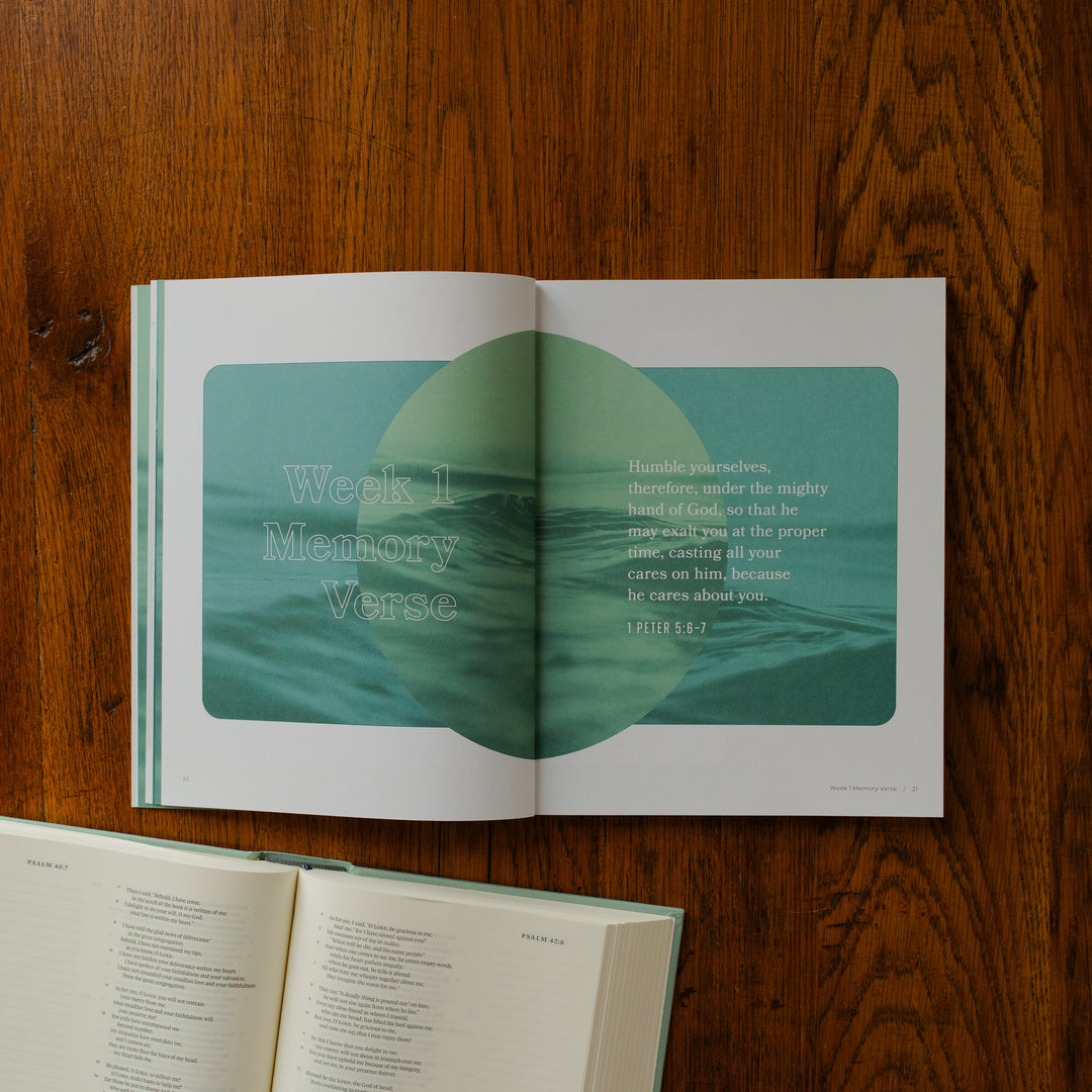 It is Well Teen Study opened to the week 1 memory verse page on a wooden table next to an open bible