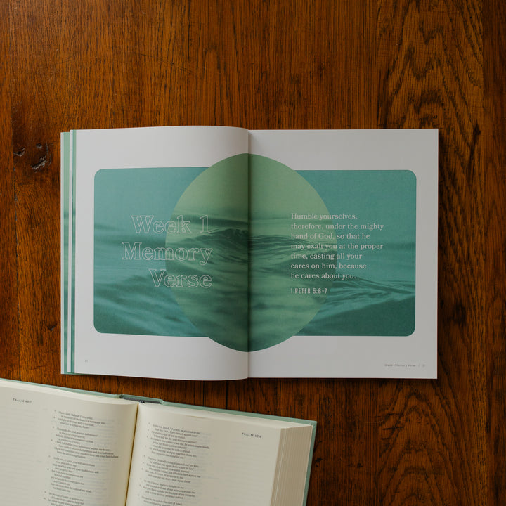 It is Well Teen Study opened to the week 1 memory verse page on a wooden table next to an open bible