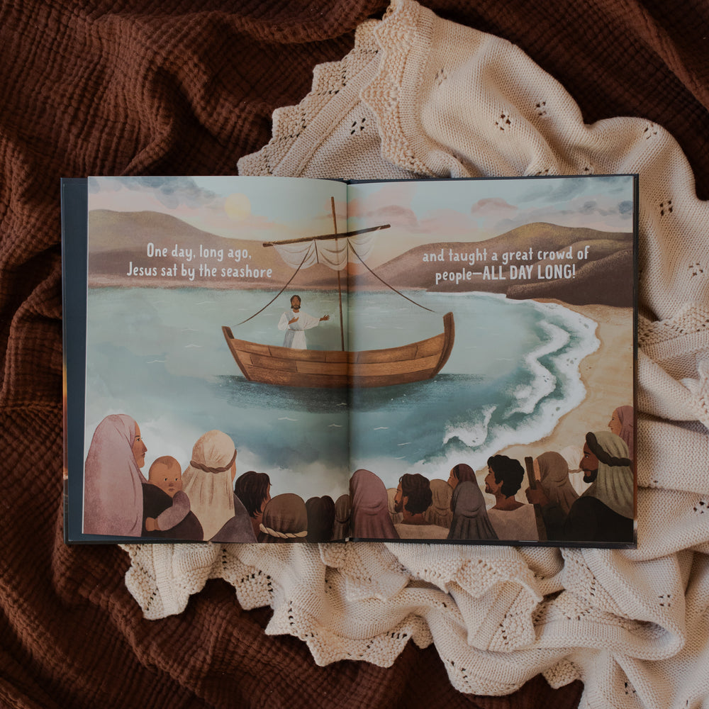 Jesus Calms the Storm Picture Book opened to Jesus on a boat page on a white and brown blanket