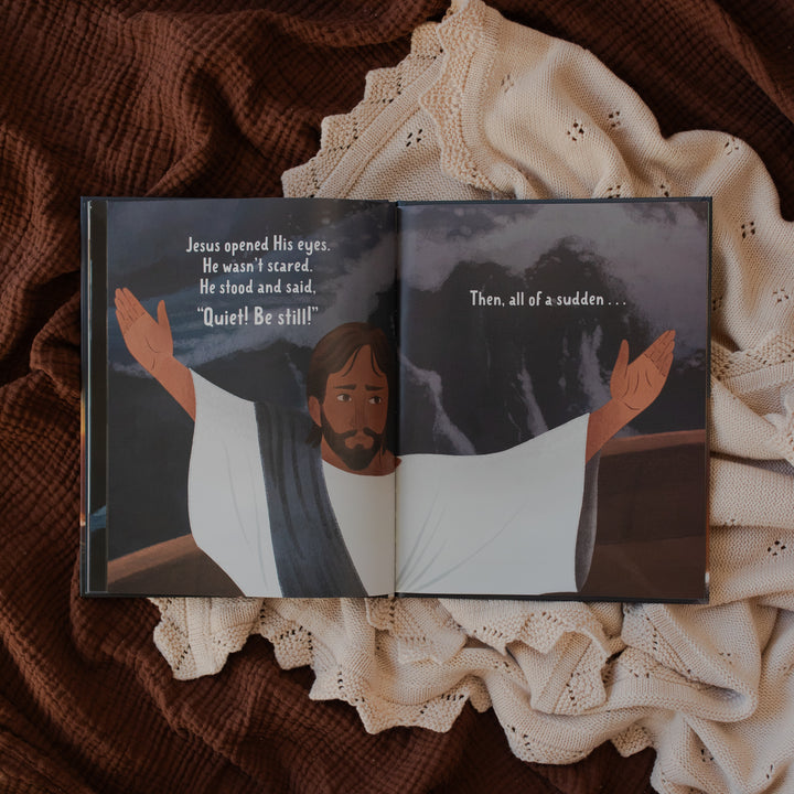 Jesus Calms the Storm Picture Book opened to Jesus calming a storm page on a white and brown blanket