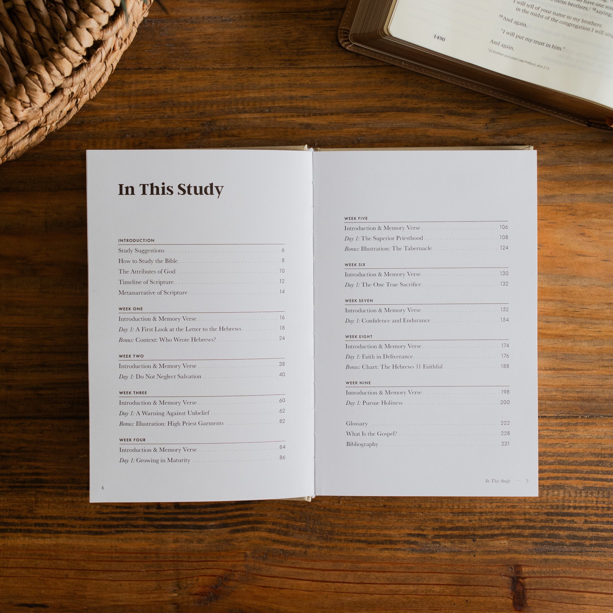 Jesus is Better Mens study opened to the table of contents page on a wooden desk next to a woven basket and an open bible