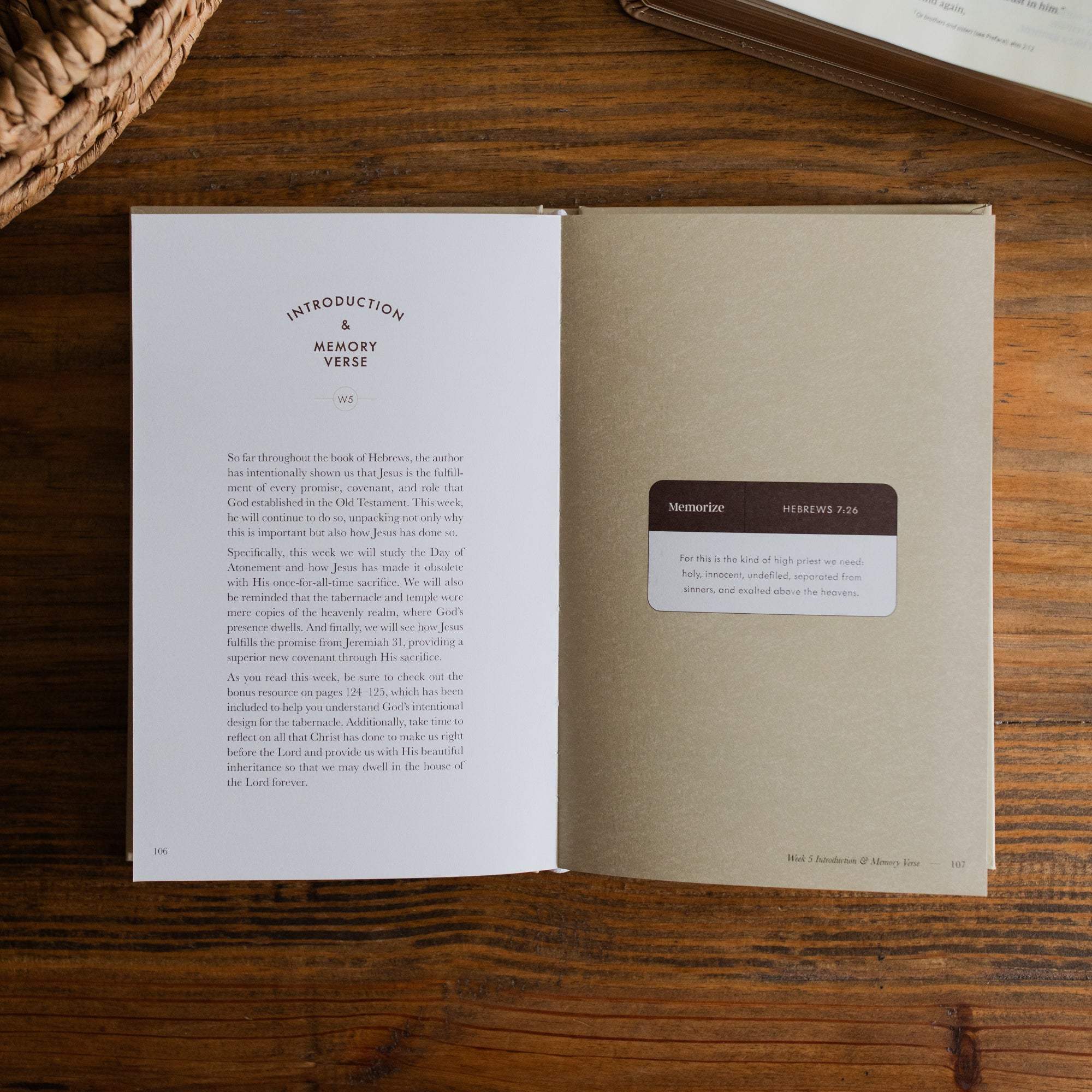 Jesus is Better Mens study opened to the Introduction and Memory Verse page on a wooden desk next to a woven basket and an open bible