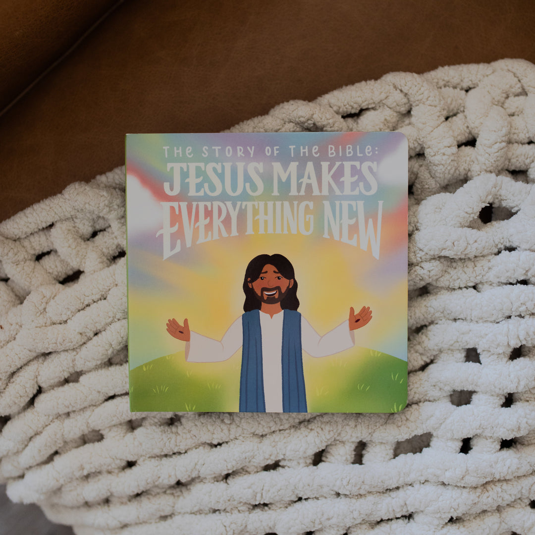 Jesus Makes Everything New Board Book laying on a white knitted blanket