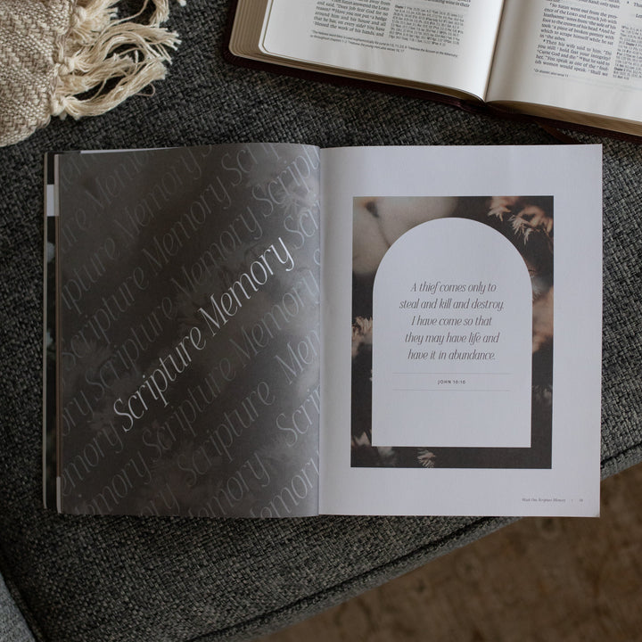 The Job study opened to the scripture memory page near an open bible on a grey couch