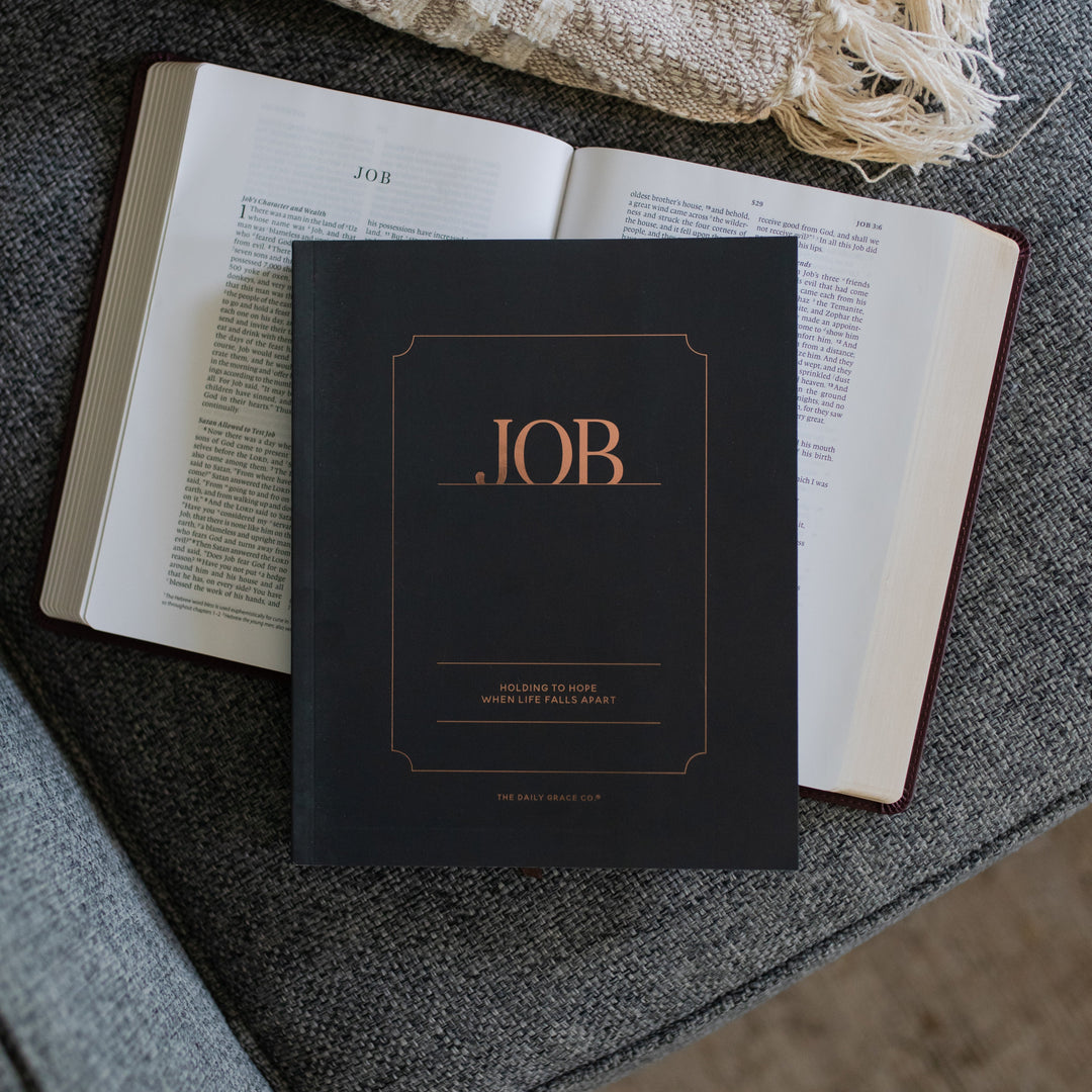 The Job Study Men's version cover laying on an open bible on a gray couch