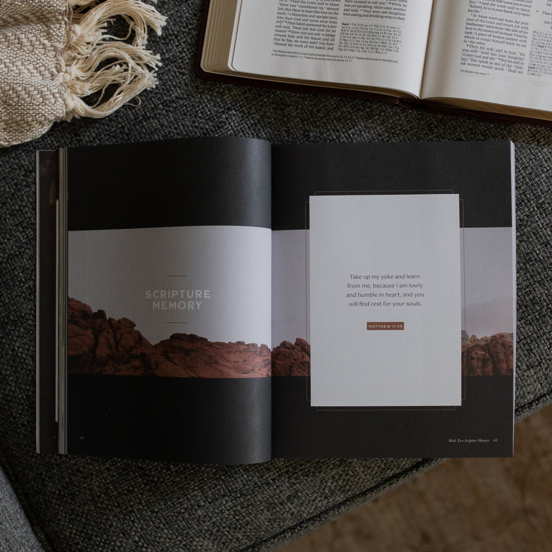 The Job Study Men's version opened to the scripture memory page next to an open bible on a gray couch