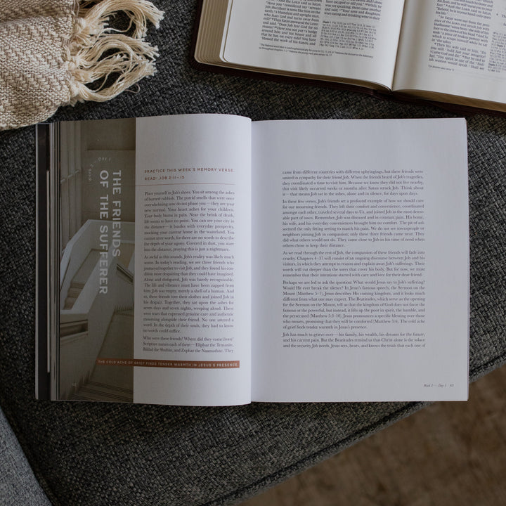 The Job Study Men's version opened to the Friends of the sufferer page next to an open bible on a gray couch