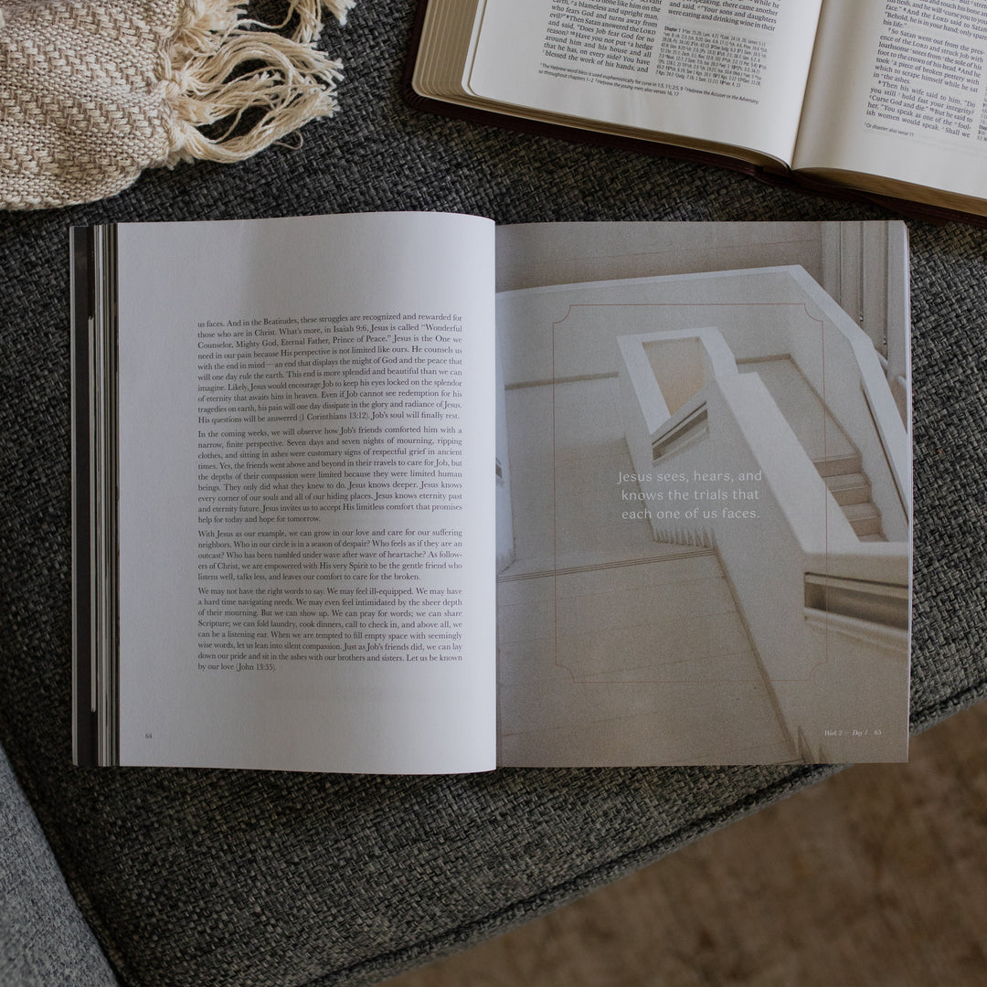 The Job Study Men's version opened to the week 2 day 1 page next to an open bible on a gray couch