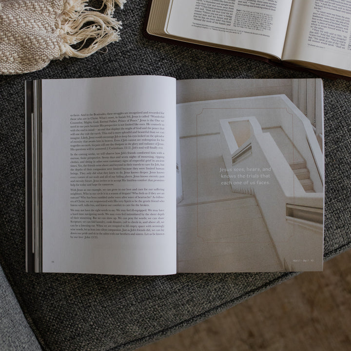 The Job Study Men's version opened to the week 2 day 1 page next to an open bible on a gray couch