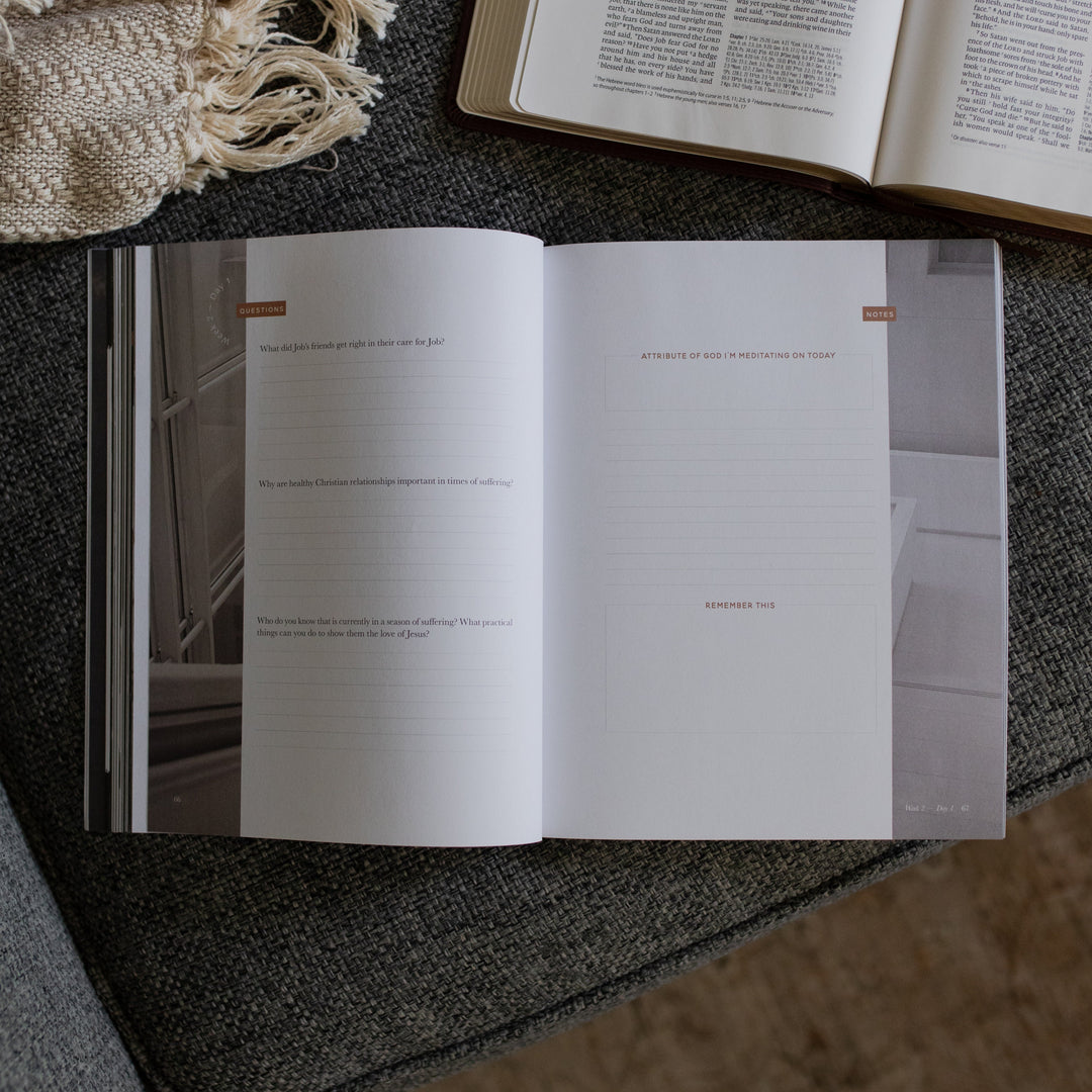 The Job Study Men's version opened to the questions and notes page next to an open bible on a gray couch