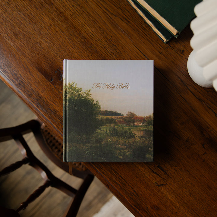A Bible on a wooden table with a scenic cover