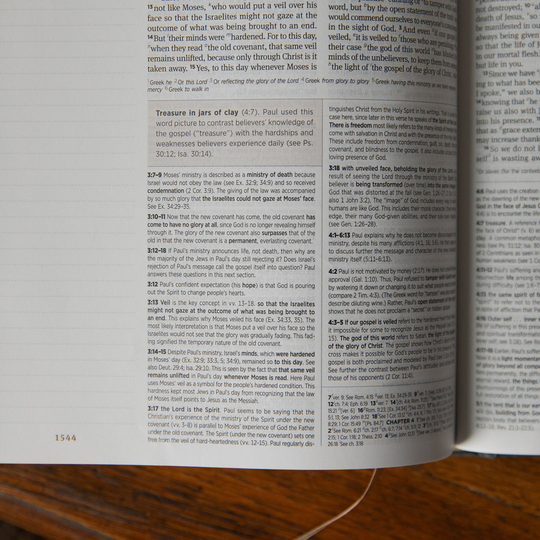 Open Bible with text on a wooden surface up close to the details section