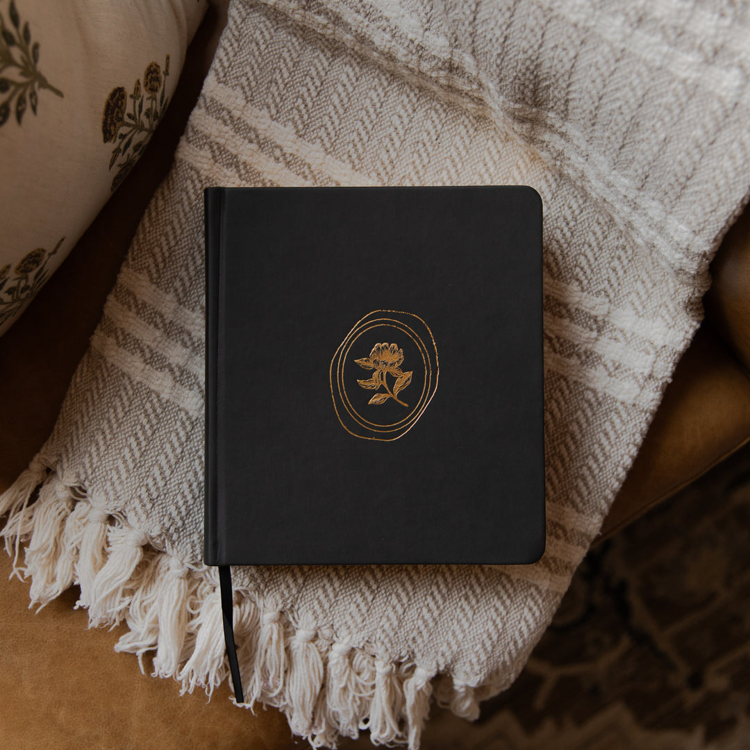 Black bible with a gold emblem on a textured blanket