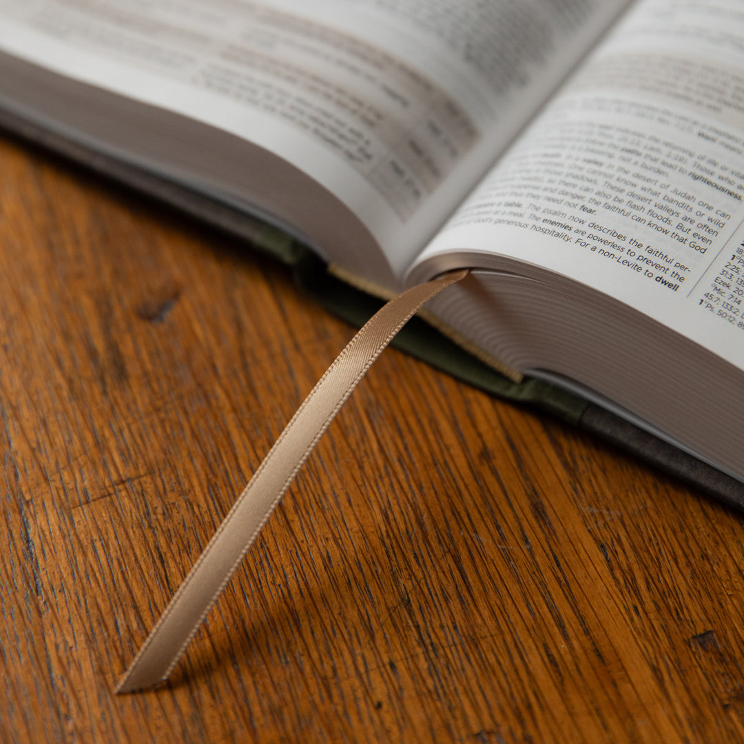 Open Bible on a wooden surface with a ribbon marker.