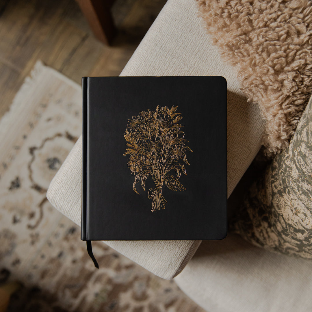Black Bible with a gold embossed design on a textured surface