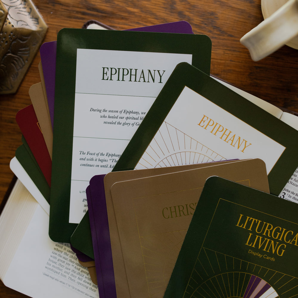 Multiple Liturgical Living Cards over an open bible on a wooden table