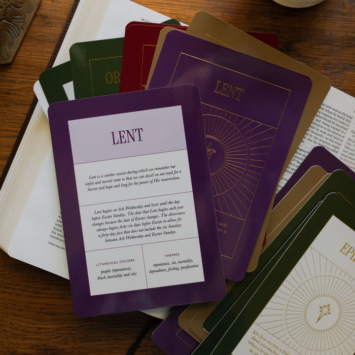 Multiple Liturgical Living Cards with the Lent context card displayed over an open bible on a wooden table