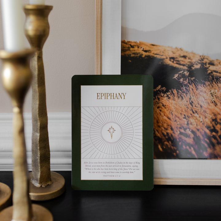 A Green Epiphany card from the Liturgical Living Display Card leaning against a painting and near candlesticks