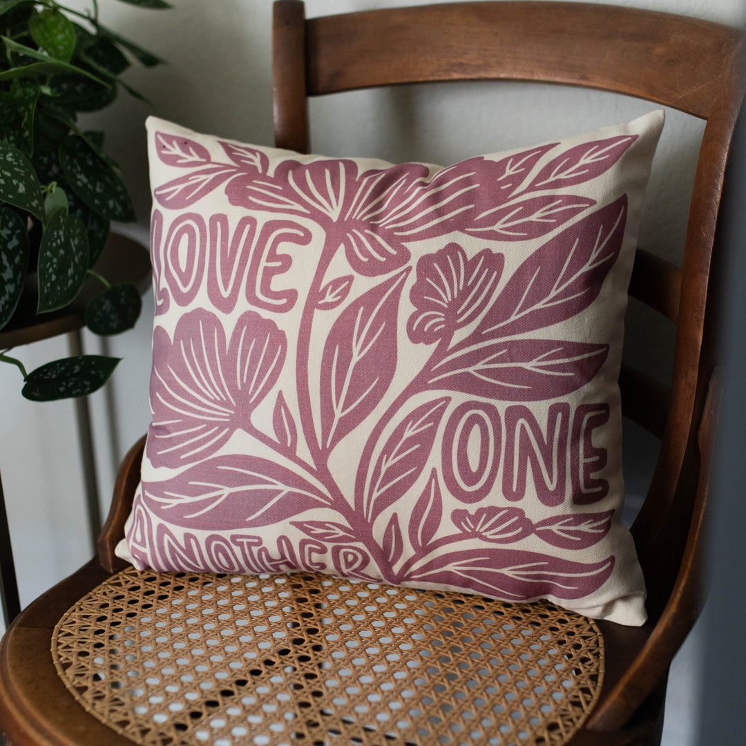 Love one another floral pillow cover on a chair