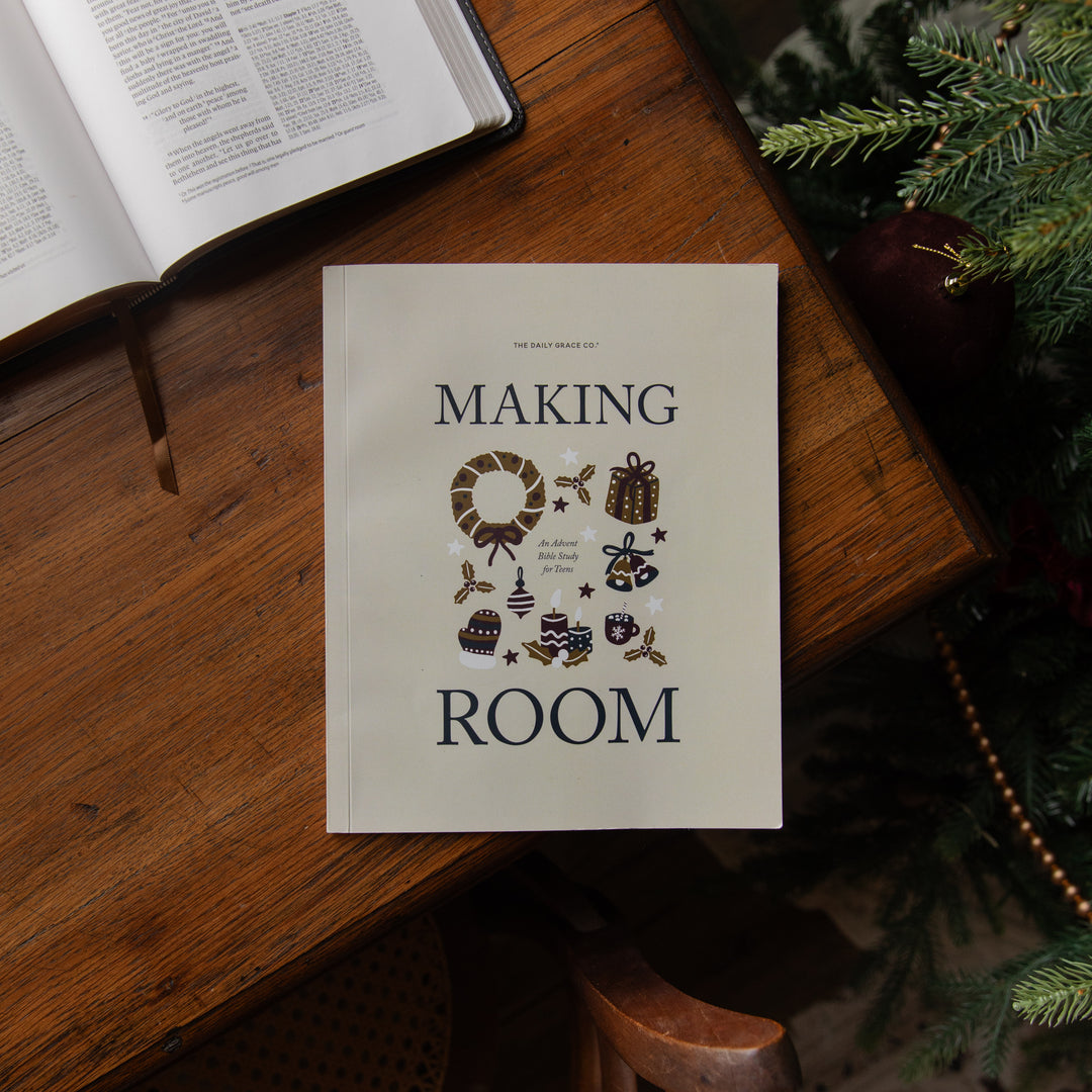 A book titled 'Making Room' by The Daily View Club is displayed on a rustic wooden table, styled with an open book and Christmas tree branches in the background.