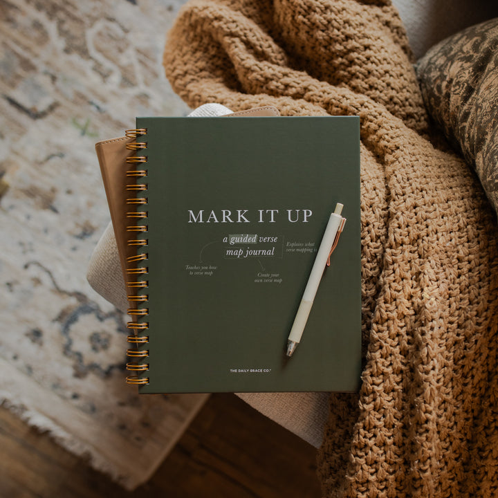 Mark It Up Journal opened to the cover page with a pen on it on a woven brown blanket