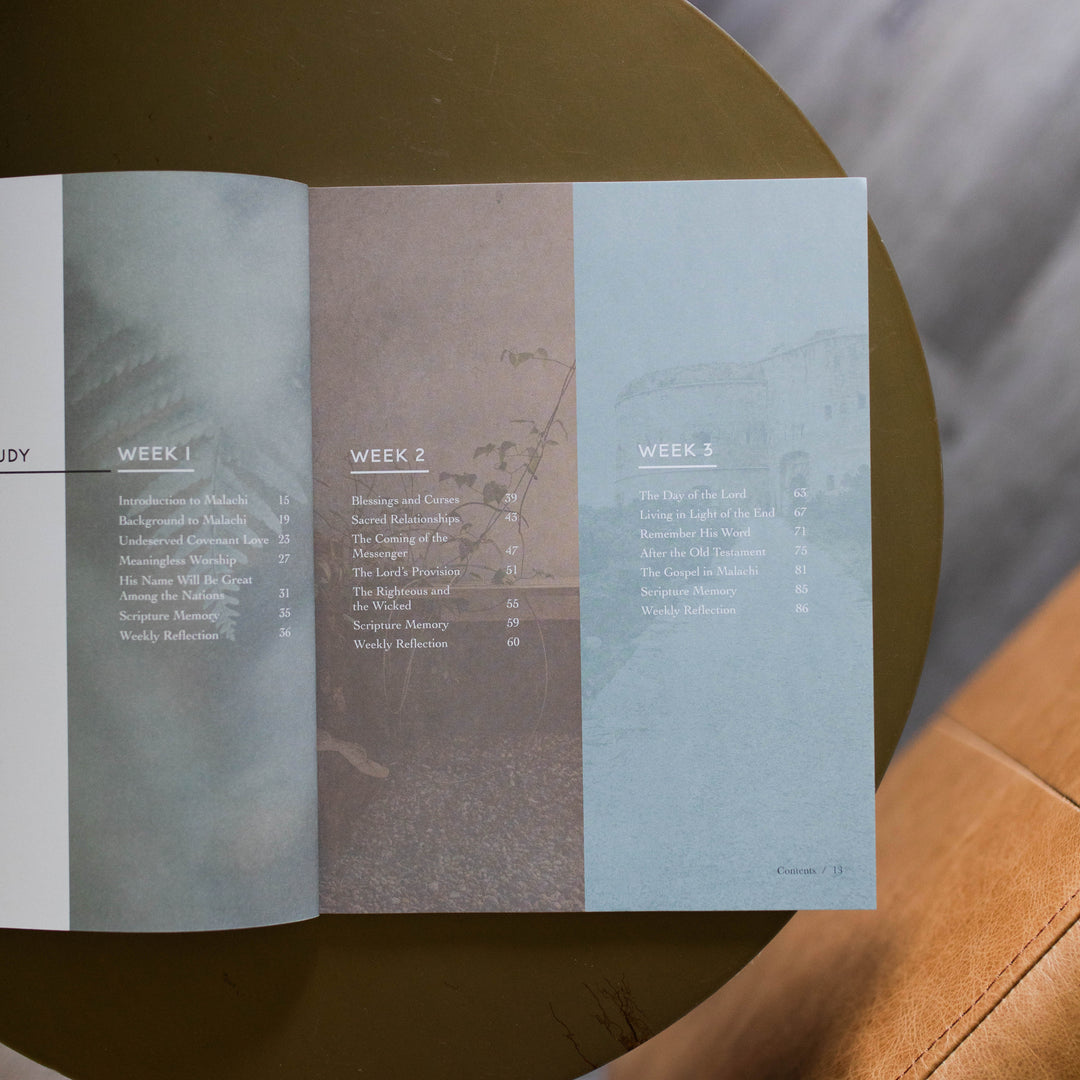 Mens Malachi Waiting for Hope Bible Study opened to a table of contents page for weeks 2 and 3 sitting on a gold colored table