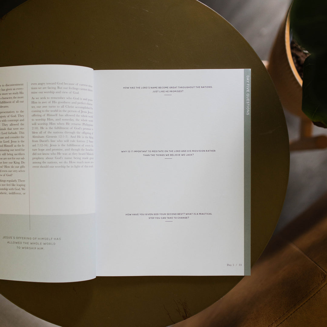 Mens Malachi Waiting for Hope Bible Study opened to Week 1s questions page sitting on a gold colored table next to a potted plant