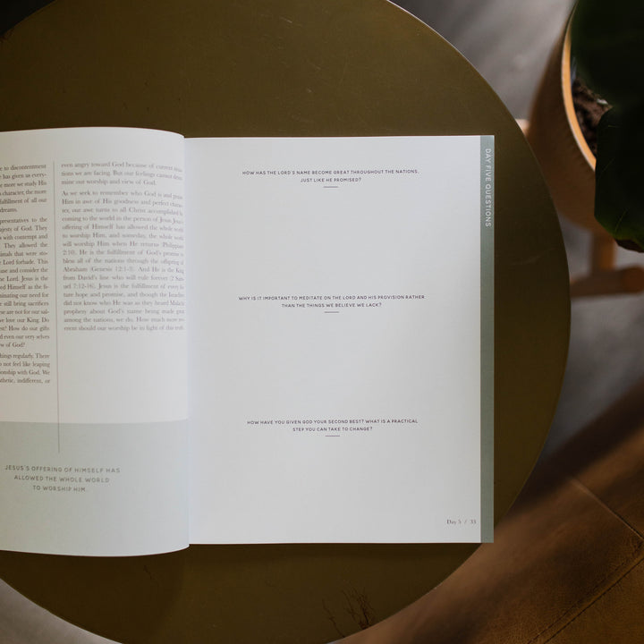 Mens Malachi Waiting for Hope Bible Study opened to Week 1s questions page sitting on a gold colored table next to a potted plant