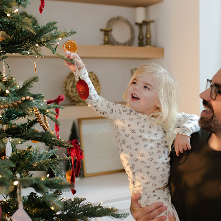 Little girl and dad hanging More Than A Manger ornament on the Christmas tree