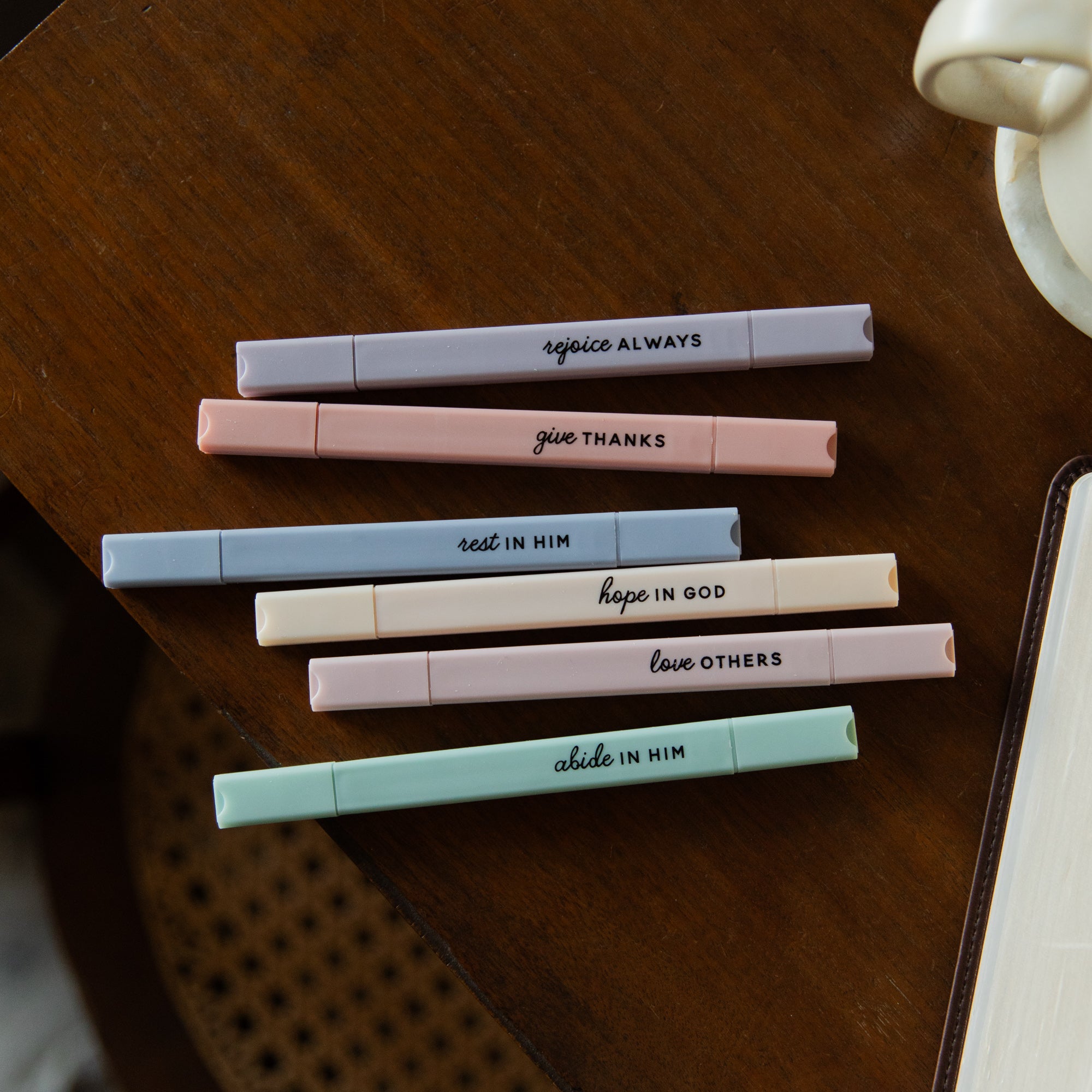 Set of pens with motivational phrases on a wooden surface
