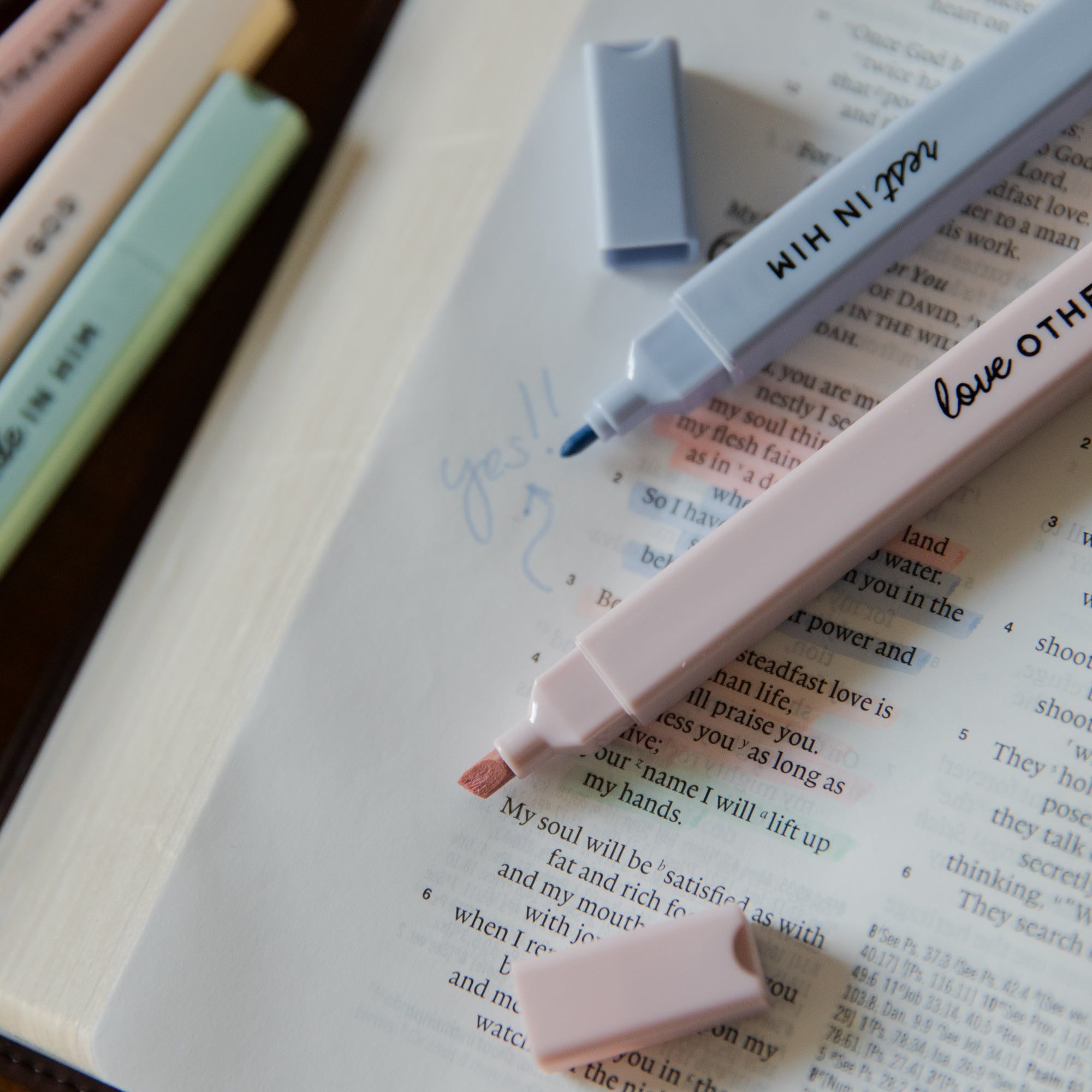 Two highlighters on an open book with text and a blue highlighter cap.