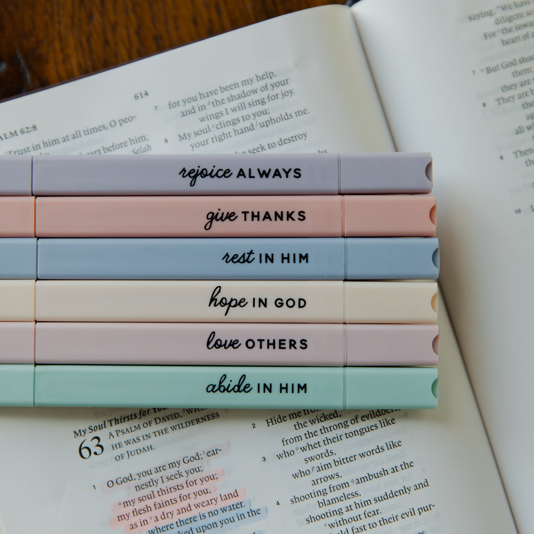 Stack of colorful pens with motivational phrases on a book