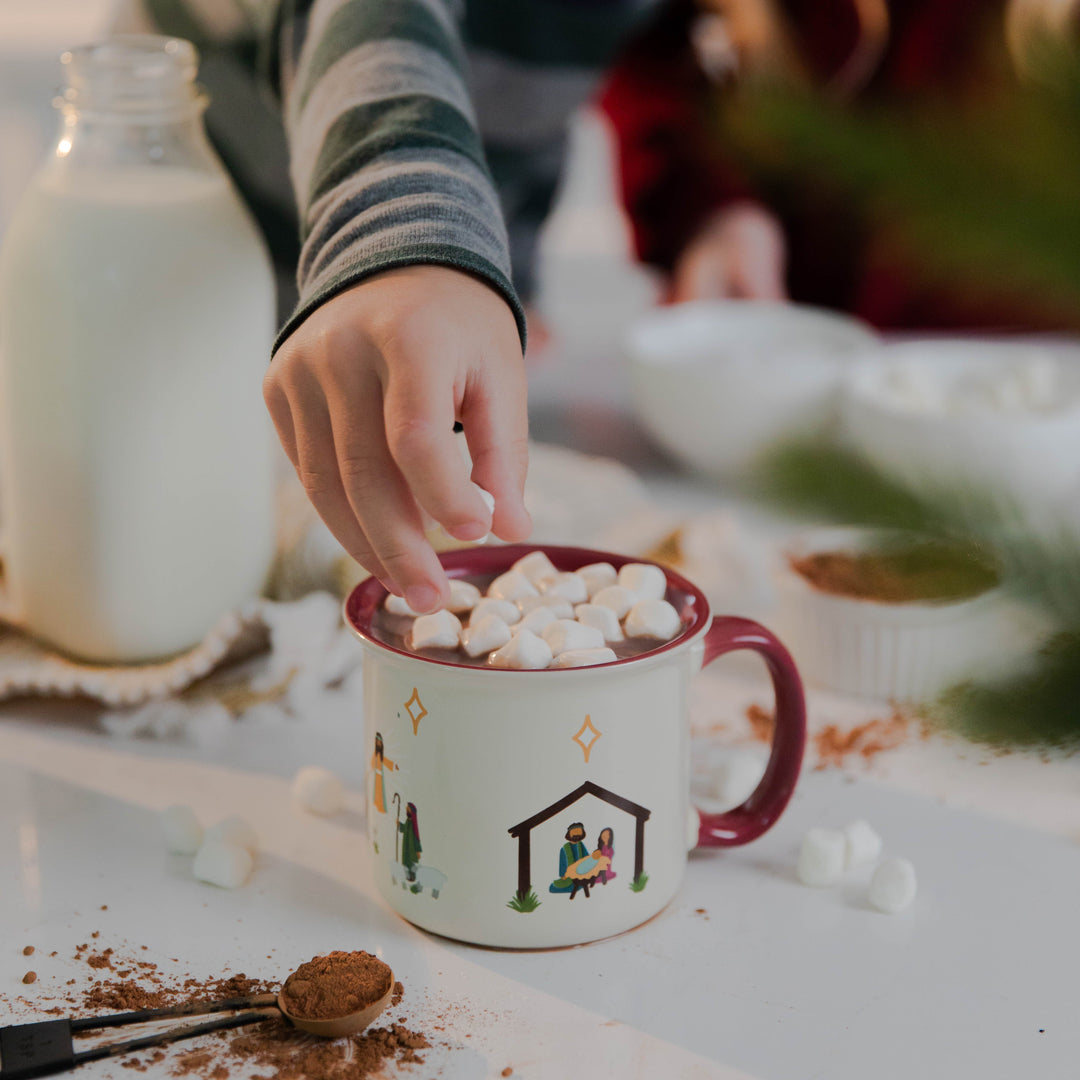 Little boy putting marshmallows in hot cocoa in Christmas Nativity Mug 