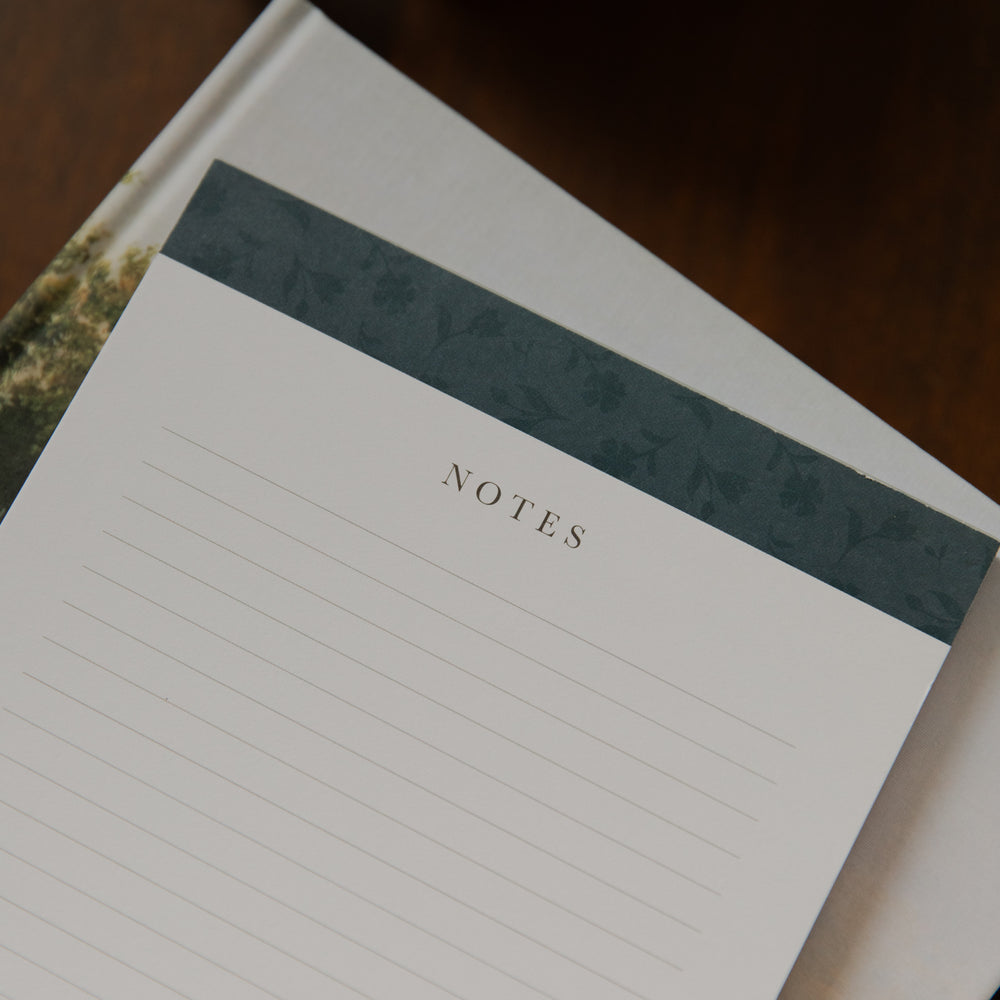 Up close of A floral notepad on a closed bible on a wooden table