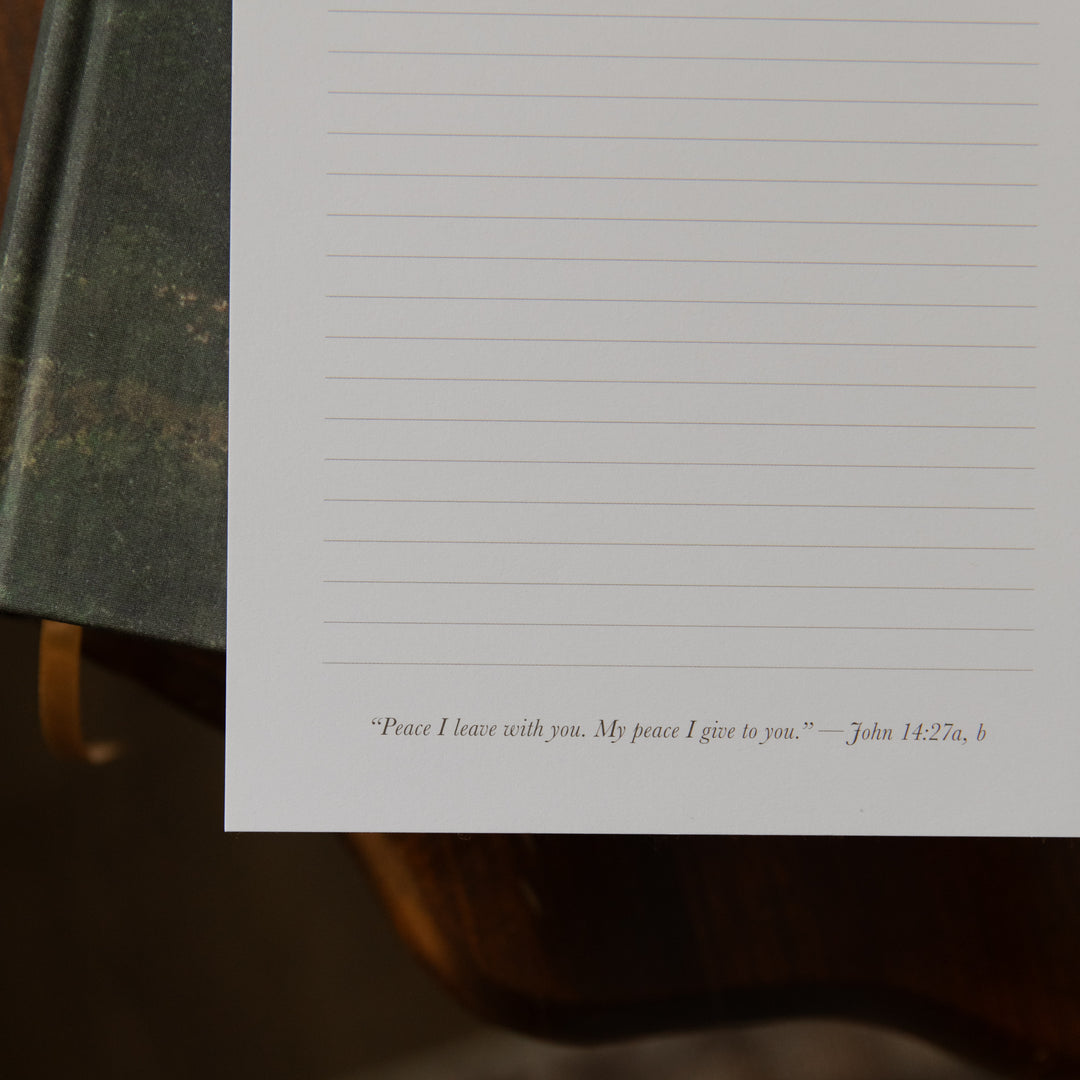 Up close of the bottom of A floral notepad on a closed bible on a wooden table