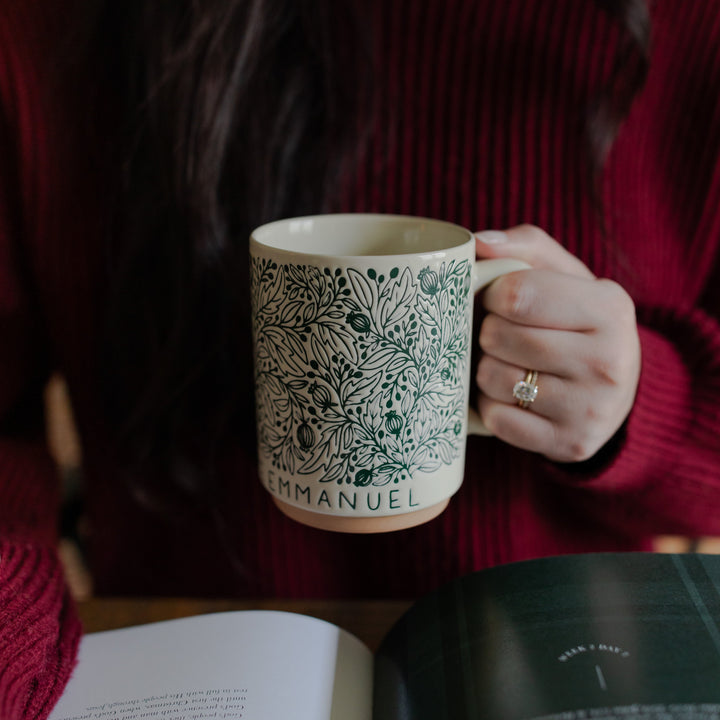 A woman holding the O Come O Come Emmanuel mug facing the camera