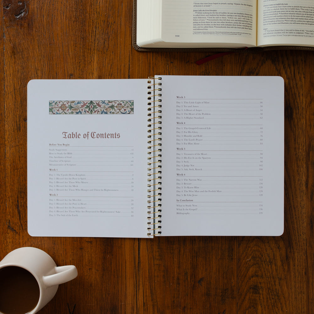 Open notebook with table of contents on a wooden surface next to a coffee cup