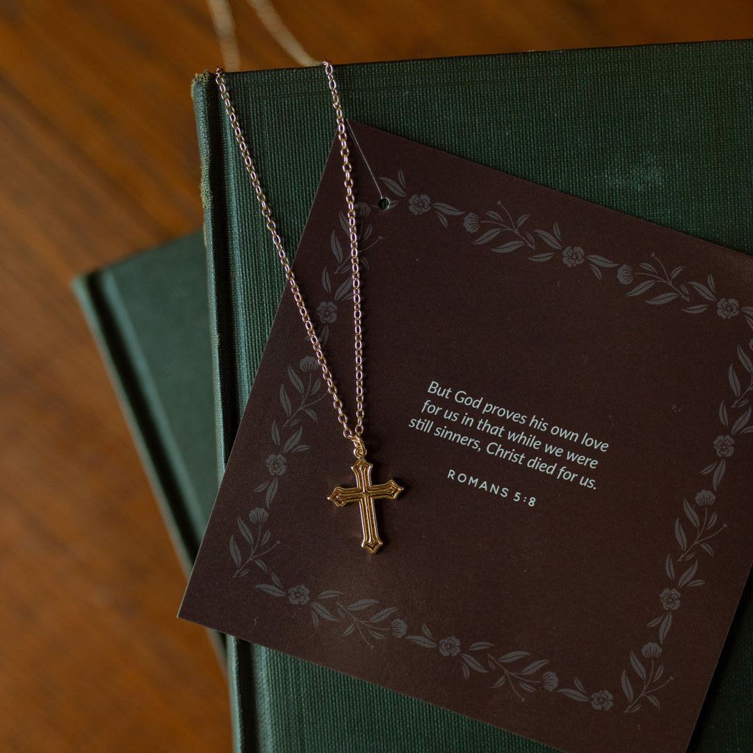 Ornate cross necklace on multiple green journals
