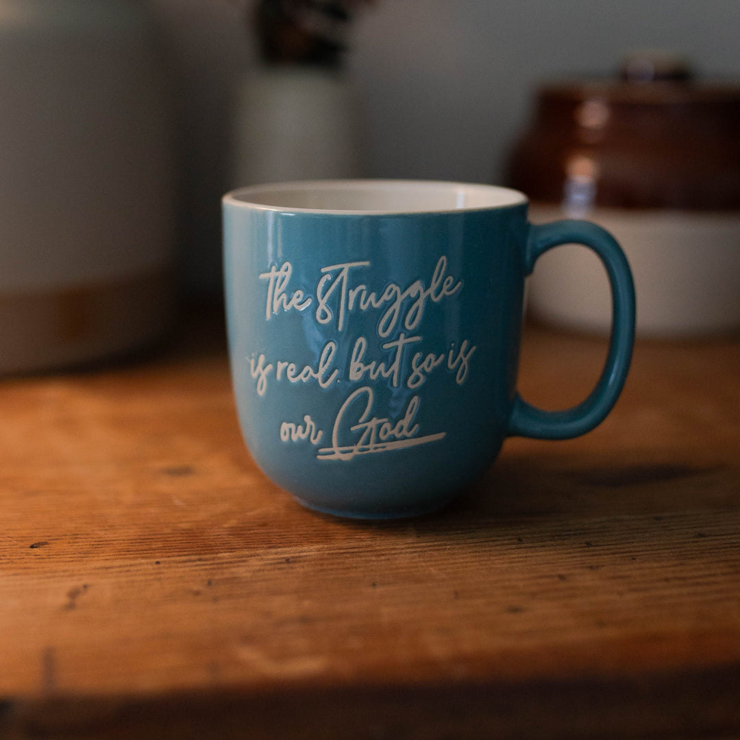 the struggle is real but so is our god ceramic christian mug on a table