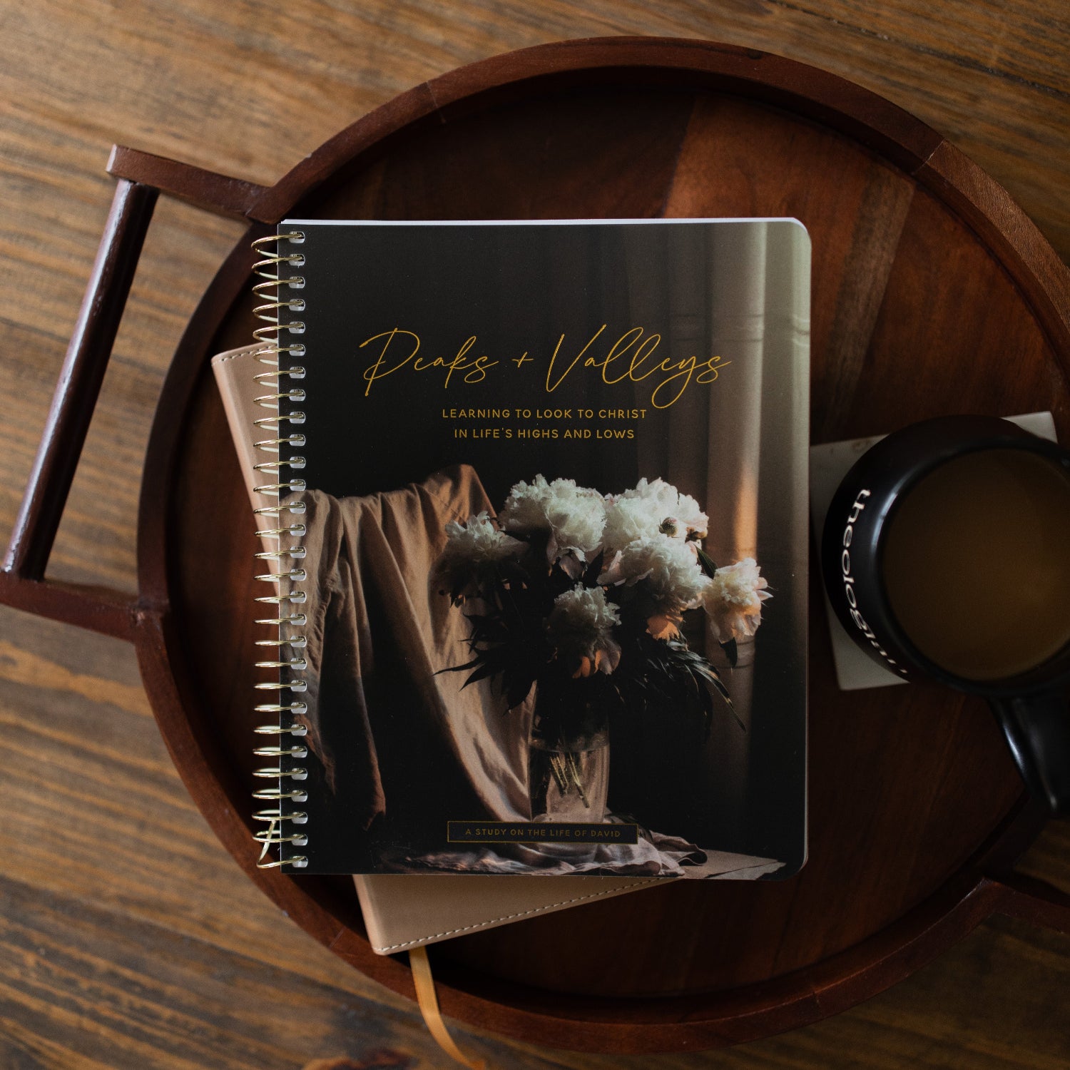 Peaks and Valleys Spiral Study on a dark brown wooden tray with a black coffee cup next to it on a brown wooden table