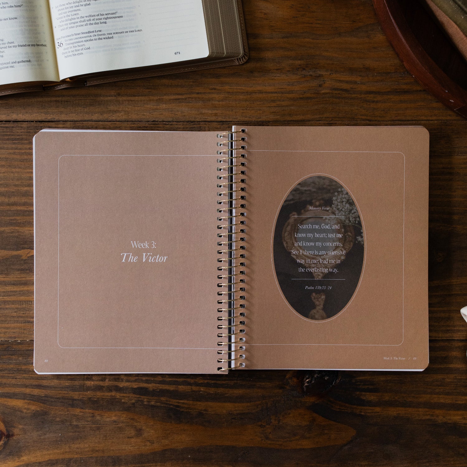Peaks and Valleys Spiral Study opened to the week 3 The Victor page next to a dark brown wooden tray and an open bible on a brown wooden table