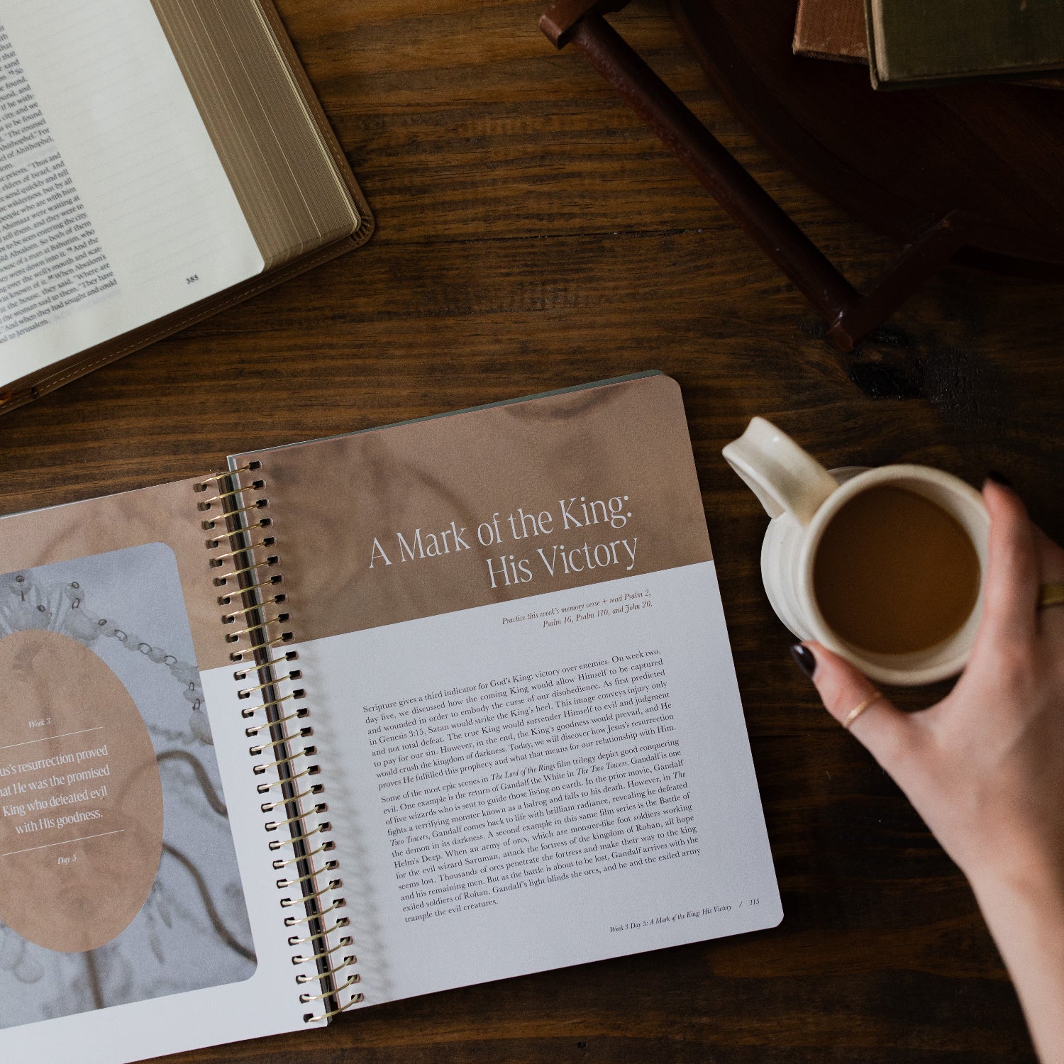 Peaks and Valleys Spiral Study opened to the Table of Contents next to a dark brown wooden tray and an open bible and a woman's hand on a white coffee cup on a brown wooden table
