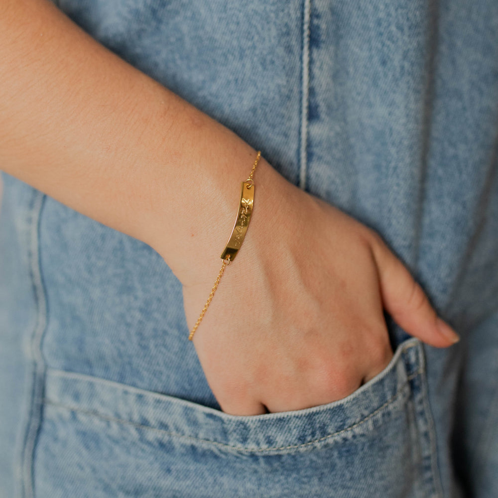 A gold chain bracelet with the word "planted" on it