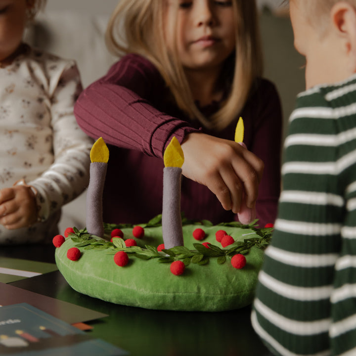 Kids touching a plush wreath on a black table
