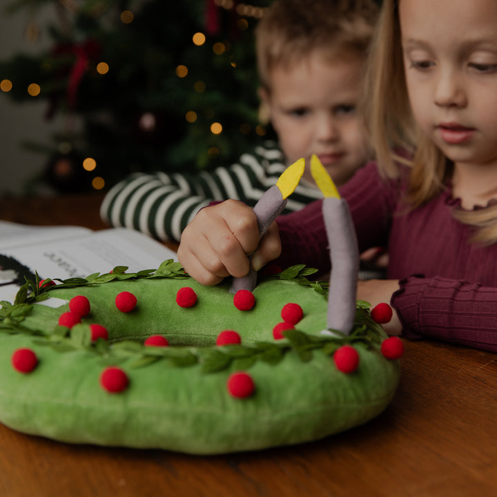 A Kids touching a plush wreath on a table